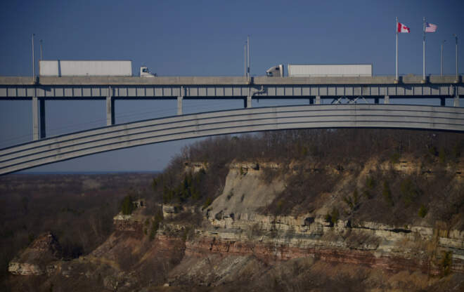 Two trucks drive toward one another on a bridge