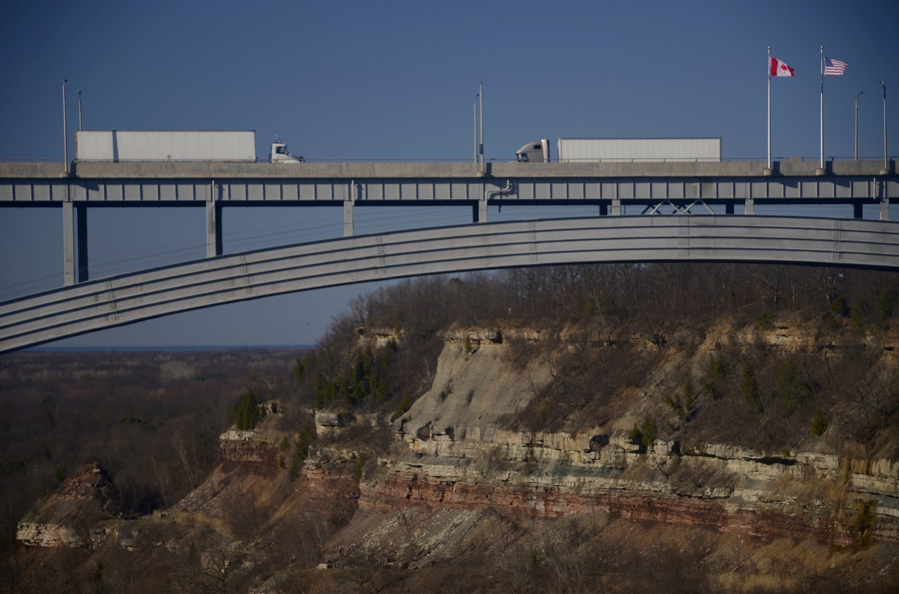 Two trucks drive toward one another on a bridge