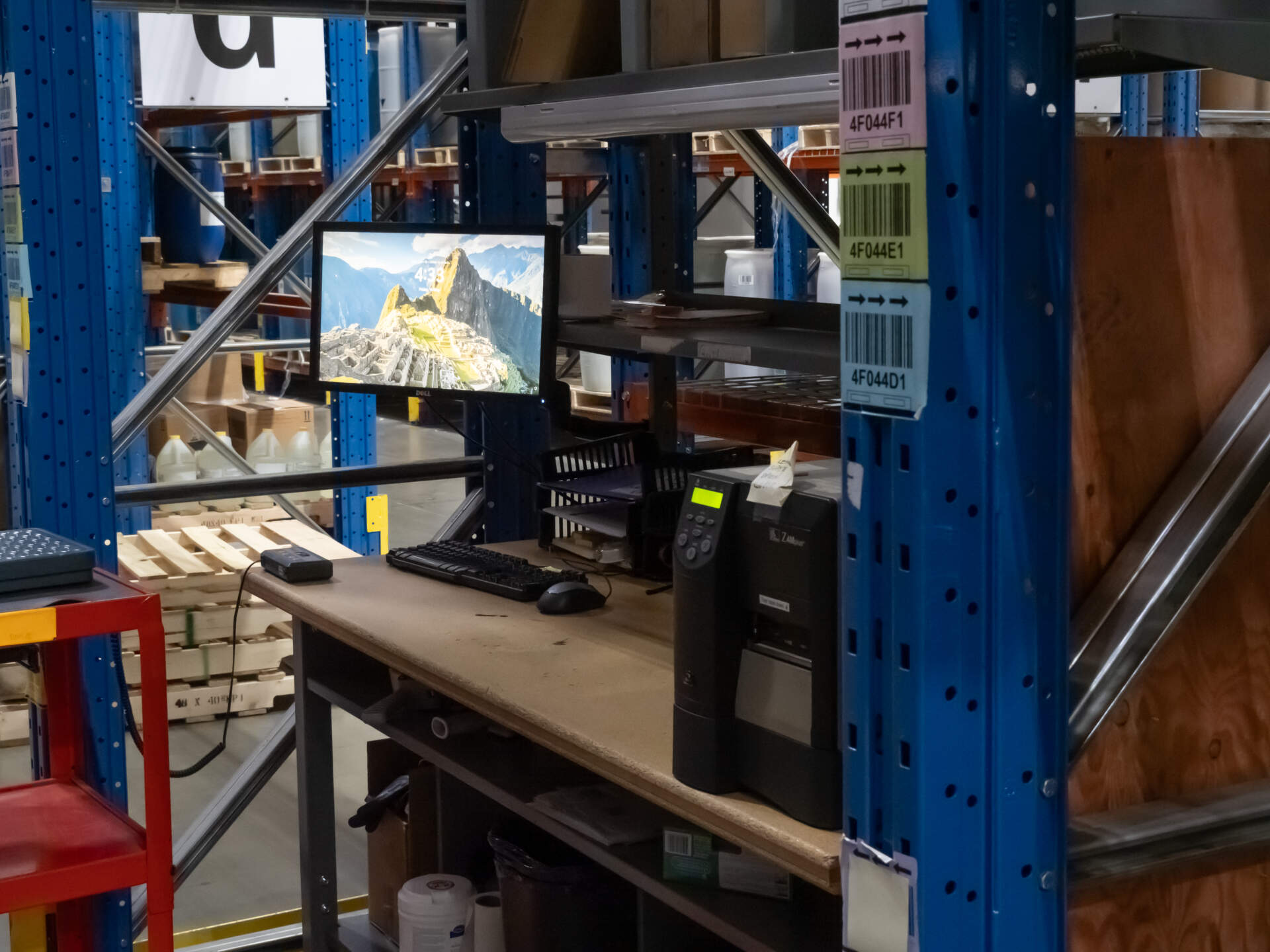 A computer screen in a warehouse depicts an environment with inventory control software.